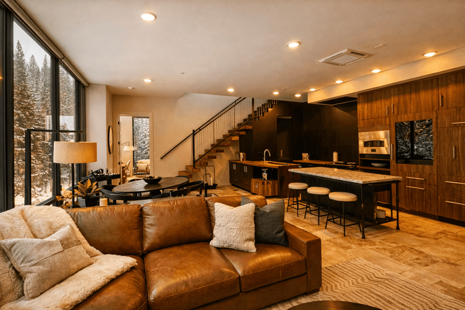 The penthouse living area, a leather sofa facing the kitchen bar and open stair